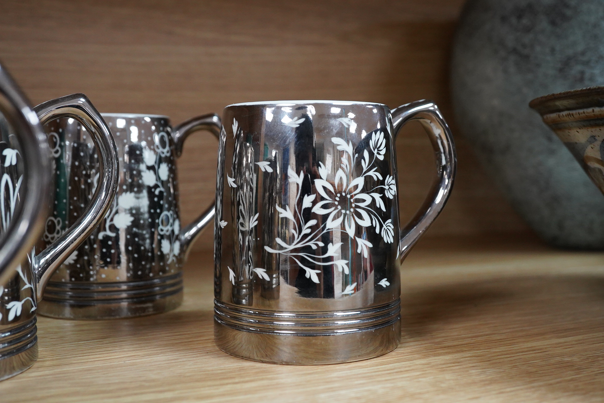 Keith Murray for Wedgwood, a set of four silvered mugs, decorated by Millicent Taplin, largest 10cm high